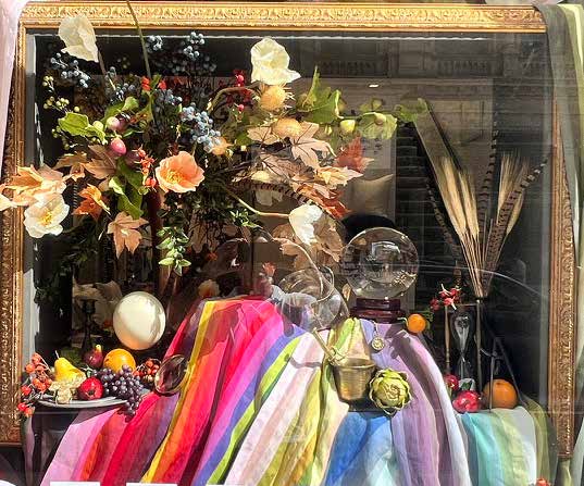 An expressive retail window display with colorful textiles, flowers and decorative objects
